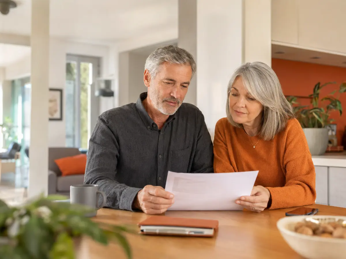 Un couple senior examine calmement un document de mutuelle dans son domicile